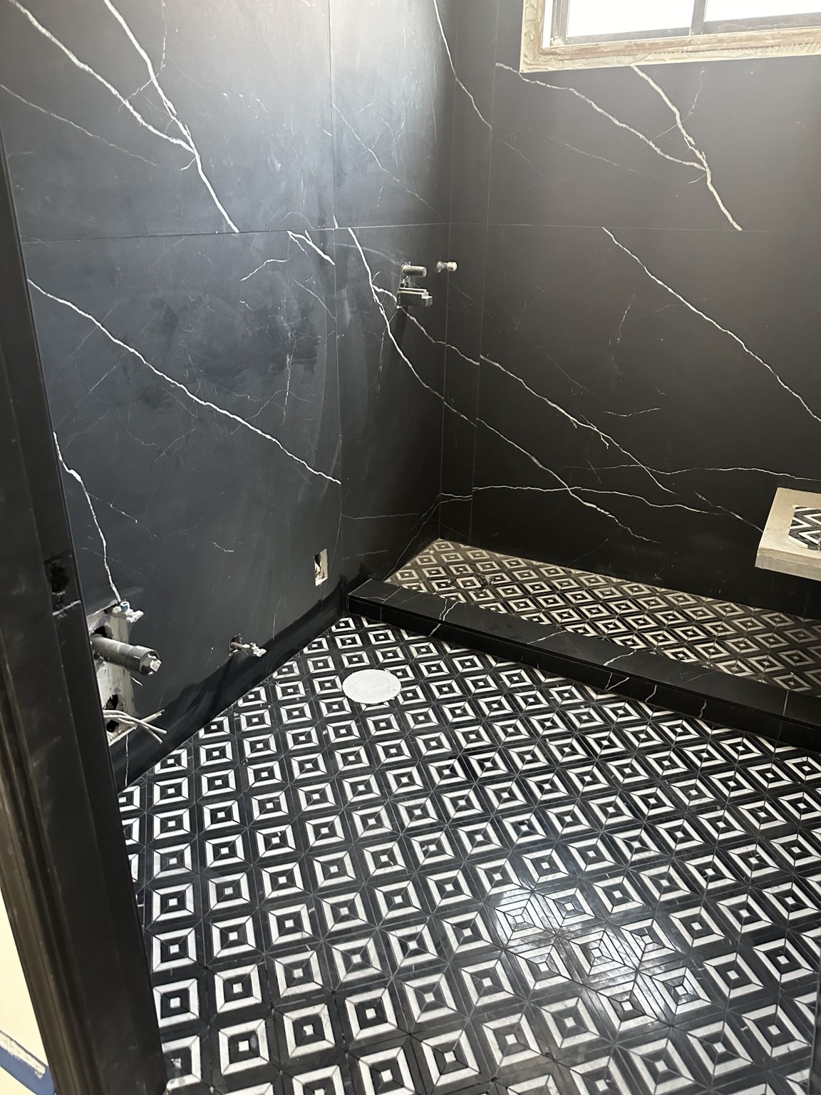 Dark stone shower and patterned floor during installation